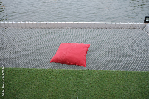 Red pillow placed on net over the river. Vacation net seat over the river.