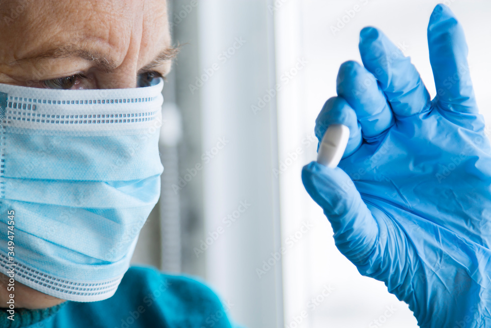 Fototapeta premium senior woman with mask and medical gloves holding pill in hand