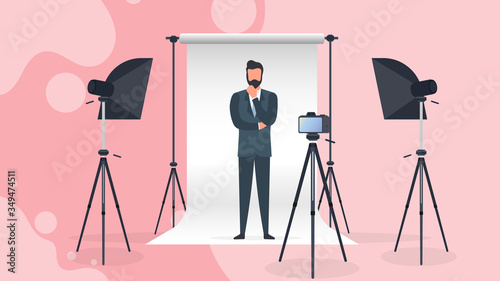 Photo Studio Vector. A man in a business suit poses for the camera. White canvas background on tripods. Camera on a tripod, softbox. Professional photo studio.