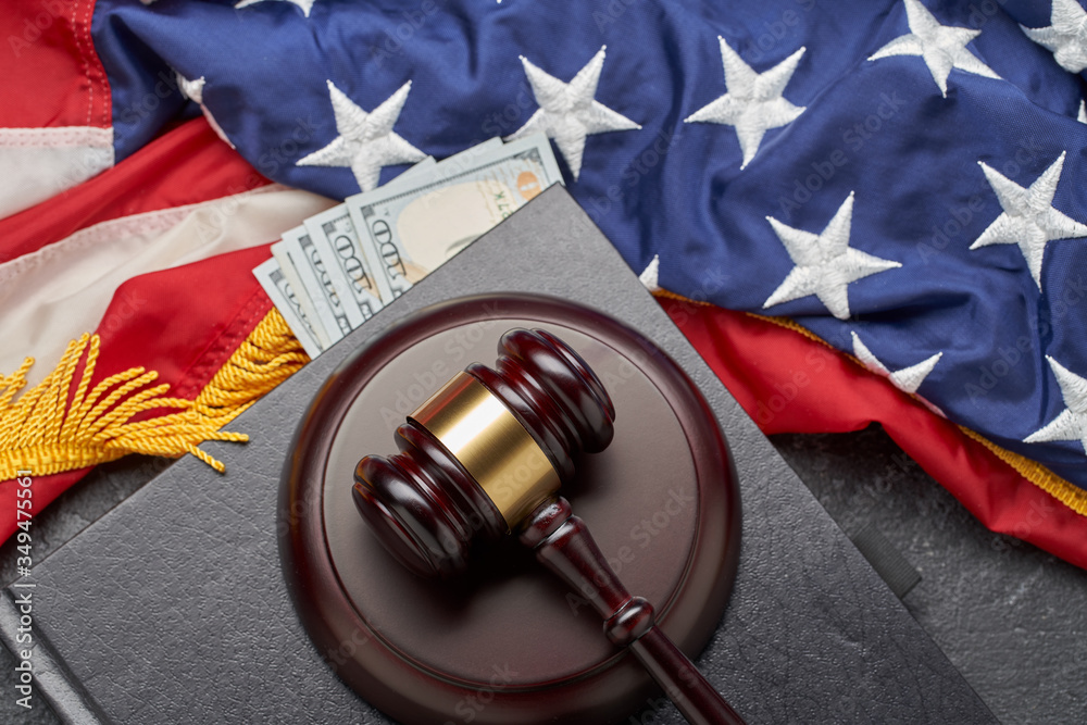 Judge gavel, banknotes on background of American flag on black surface