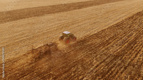 Cultivation of the agricultural field after harvesting. Top view of tractor working on the field. Preparation of field for sowing.