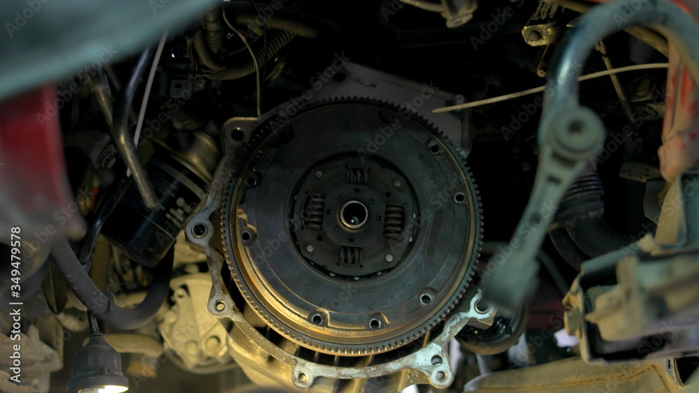 Mechanic is uninstalling a car clutch. Car service worler with diry hands taking off car clutch close up. Mechanic is uninstalling a car clutch. Car service worler with diry hands taking off car clutch close up.