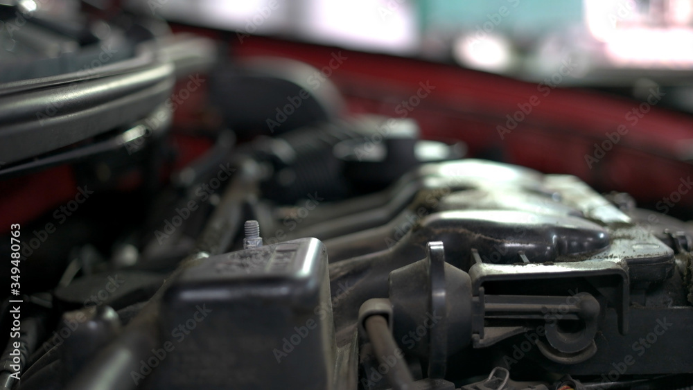 Mechanic is unscrewing car engine detail. Close up hands of a car service worker.