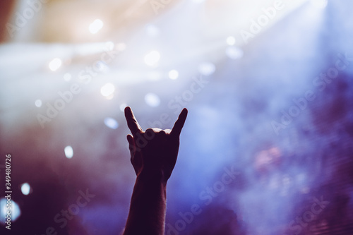 Fototapeta Naklejka Na Ścianę i Meble -  Horns raised up by a metalhead in the crowd in front of stage during the band's performance
