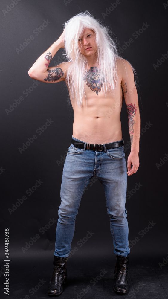 Full body shot of rebellious man as punk rocker wearing wig Full body shot of rebellious man as punk rocker wearing wig