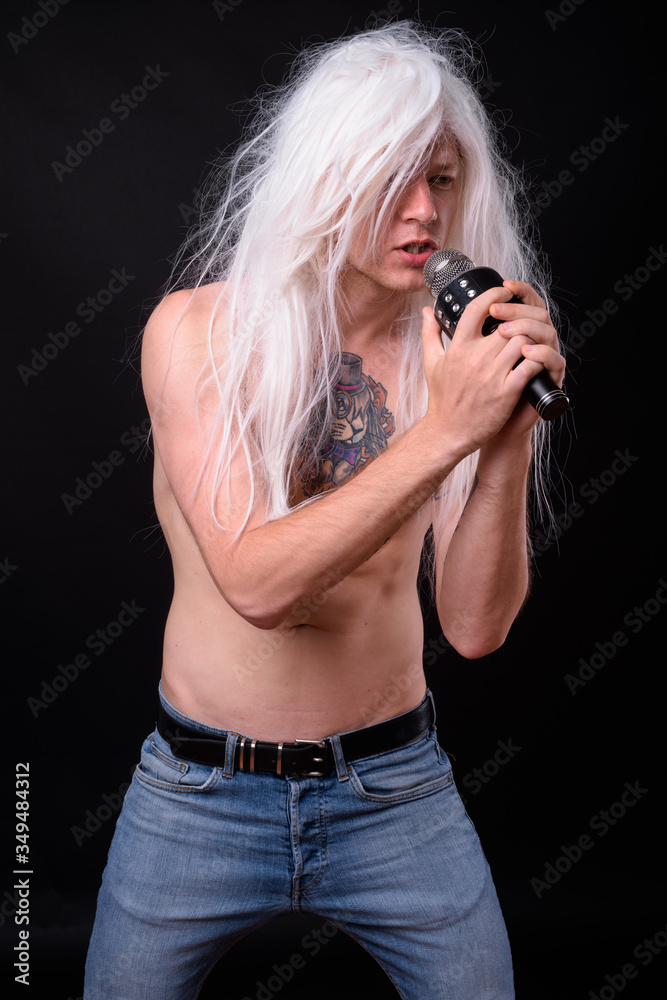 Punk rocker man wearing wig against black background Punk rocker man wearing wig against black background