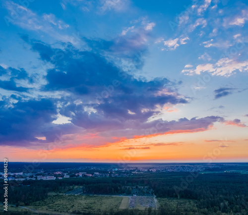 Sunset sky with clouds. The sun shines on the clouds after sunset. Beautiful nature with glam and forest. Aerial view