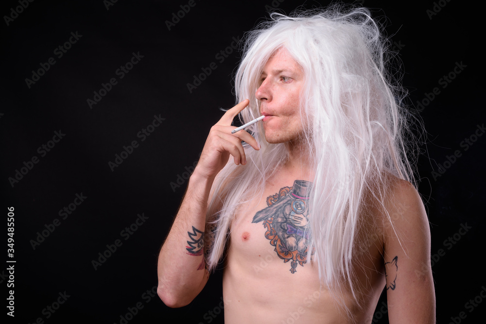 Punk rocker man wearing wig against black background Punk rocker man wearing wig against black background