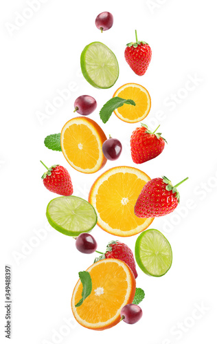 Set of different cut fresh fruits and berries falling on white background