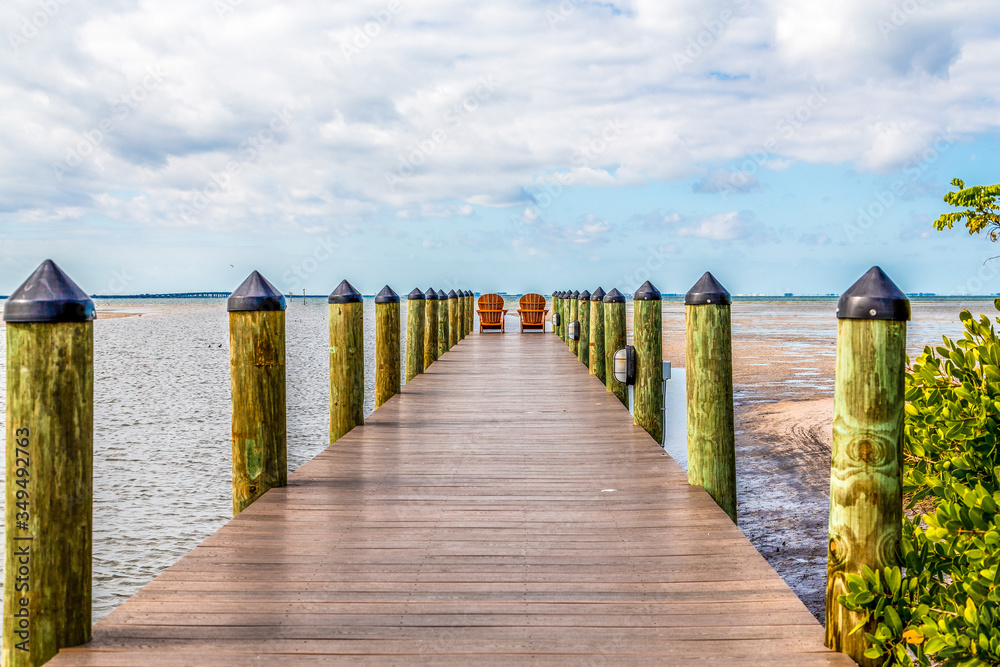 Obraz premium Adirondack chairs on a wooden pier in the tropics