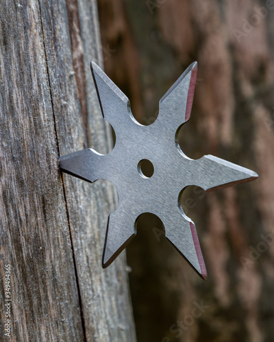 Shuriken (throwing star), traditional japanese ninja cold weapon stuck in wooden background