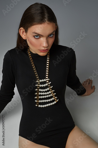 Obraz na plátně A ravishing brunette lady in a black bodysuit and a trendy choker is sitting on the gray floor