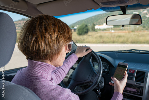 Woman driving looking at mobile phone and without seat belt photo