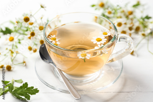 Fresh chamomile tea in cup on white wooden table