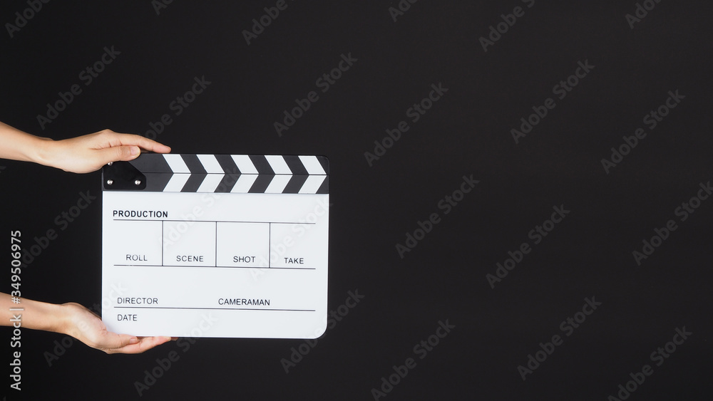 TWO Hands is holding white Clapperboard or movie slate. it use in video production ,film, cinema industry on BLACK background.