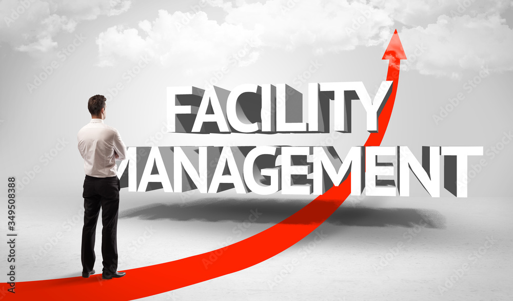 Rear view of a businessman standing in front of FACILITY MANAGEMENT inscription, successful business concept Rear view of a businessman standing in front of FACILITY MANAGEMENT inscription, successful business concept