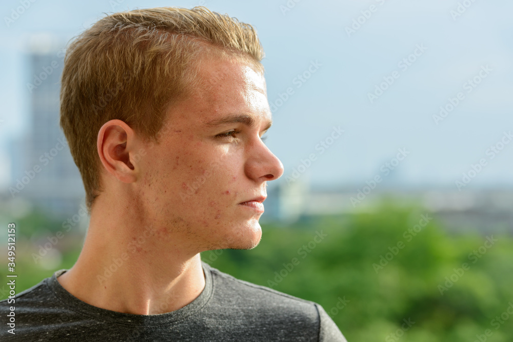 Closeup profile view of young handsome man with blond hair outdoors Closeup profile view of young handsome man with blond hair outdoors