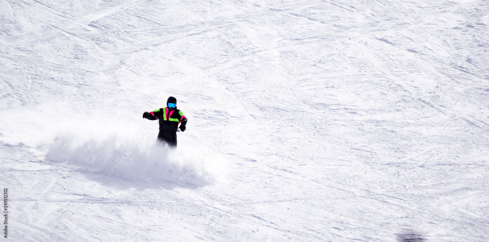 Full length of skier skiing on fresh powder snow. Man skier running downhill on sunny Alps slope