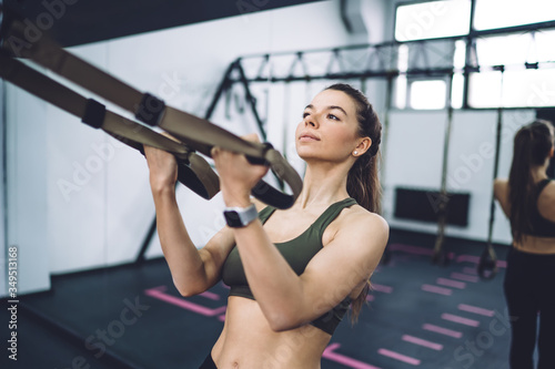 Focused young sporty woman working out in fitness center