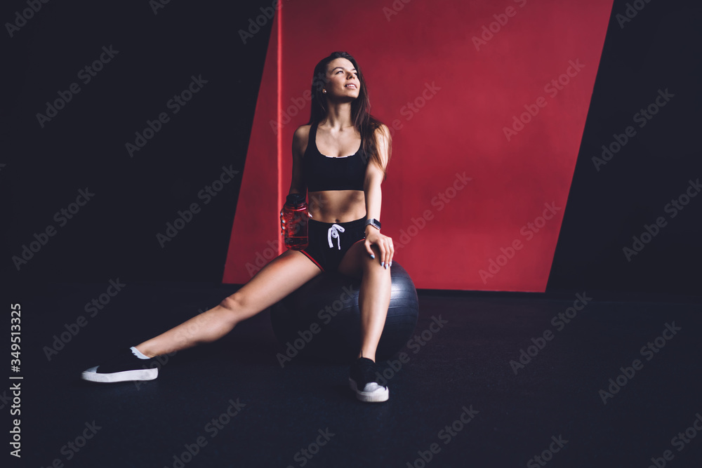 Contemporary sportswoman sitting on fitness ball