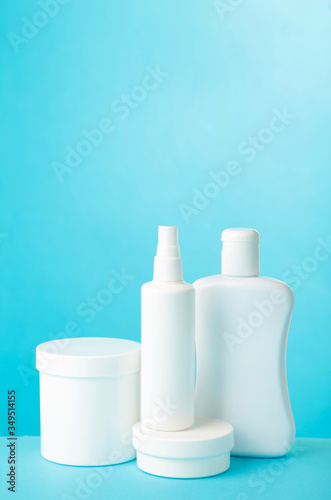 White cosmetic bottles on blue background. Top view