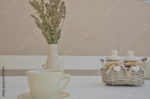 bouquet of lavender flowers in vase and tea cupin white table back yard