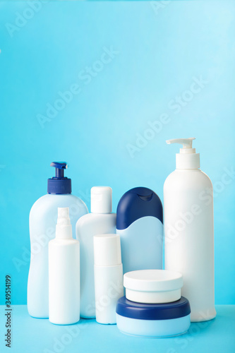 Different cosmetic bottles on blue background. Top view