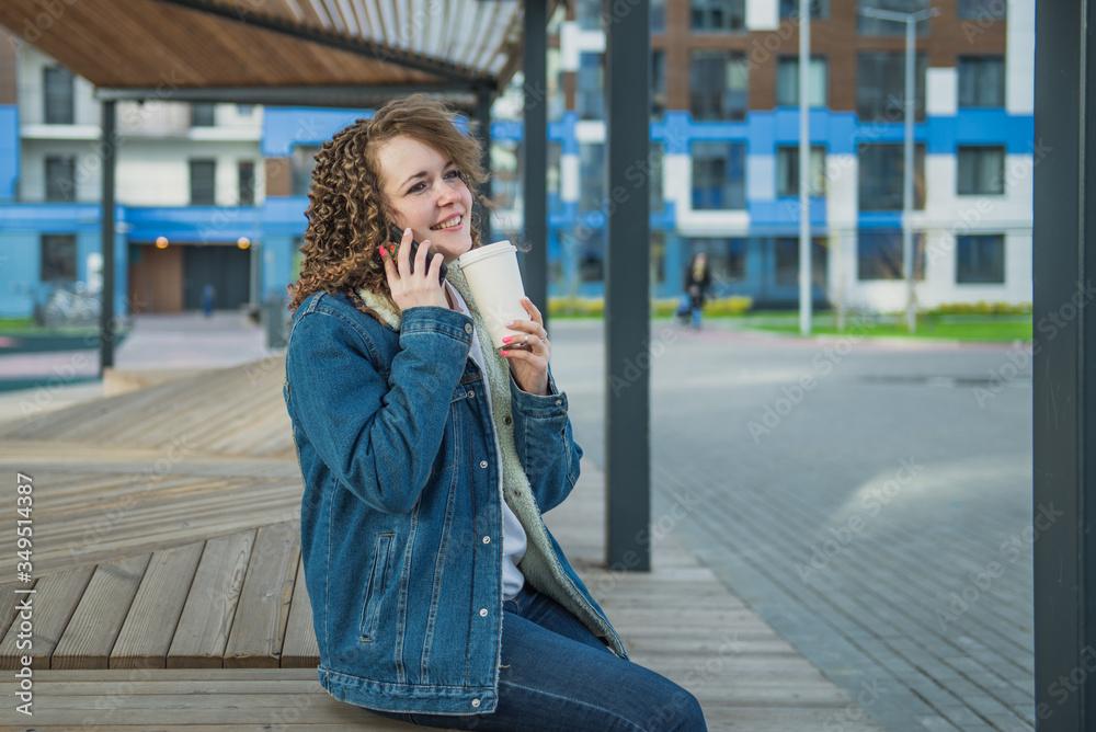 Fototapeta premium Happy girl sitting in the yard of the house and drinking coffee from a Cup
