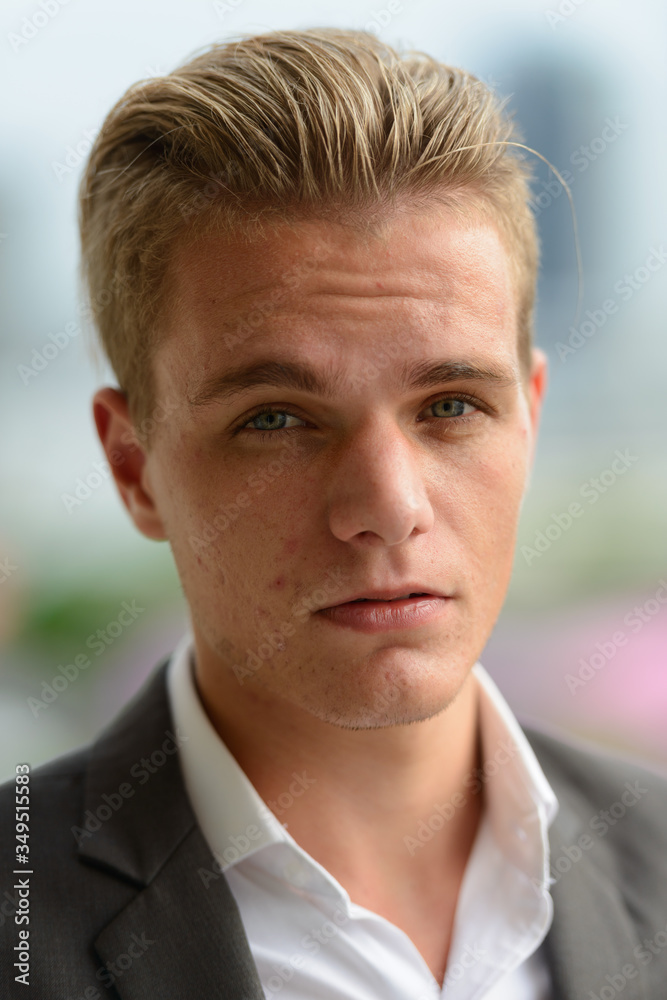 Obraz premium Face of young handsome blond businessman in suit outdoors