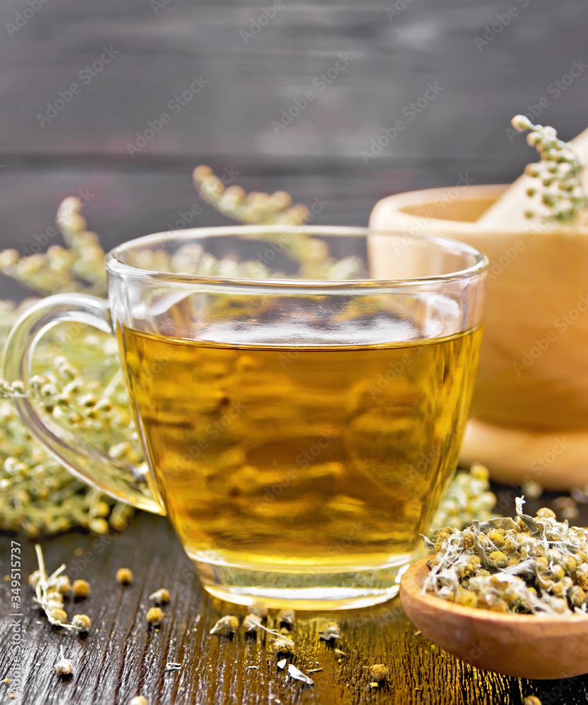 Tea of gray wormwood in glass cup with mortar on board Tea of gray wormwood in glass cup with mortar on board