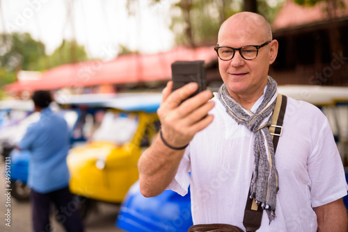 Portrait of happy senior tourist man using phone in Ayutthaya