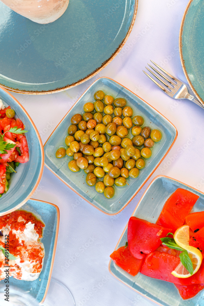 appetizers with yogurt, tomatoes, cheese, lemon, greens, mussels, olives, snacks on white background, ready for service, should be used as background. appetizers with yogurt, tomatoes, cheese, lemon, greens, mussels, olives, snacks on white background, ready for service, should be used as background.
