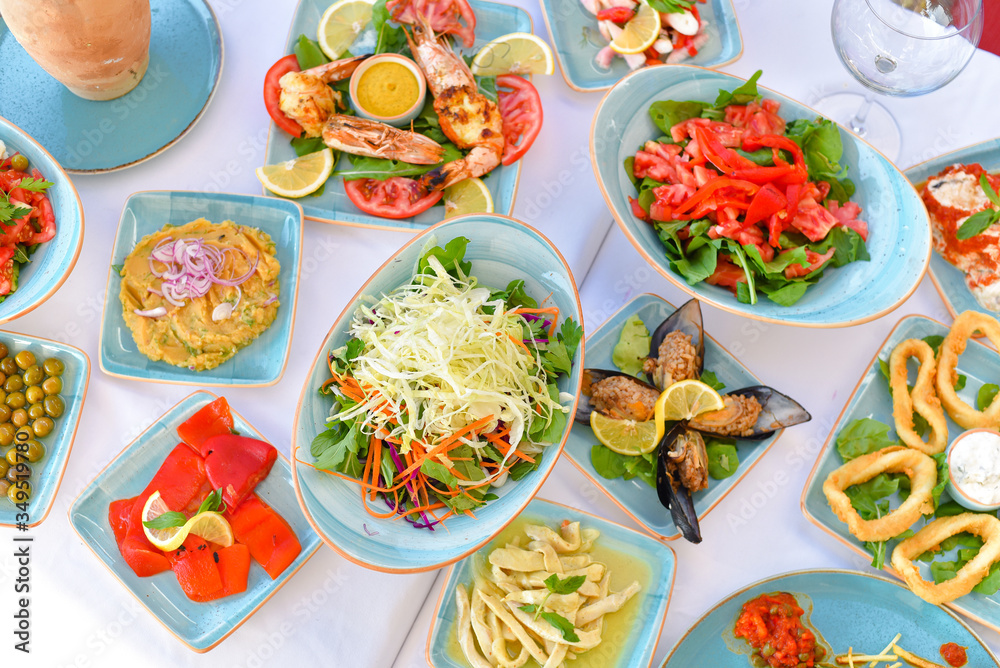 appetizers with yogurt, tomatoes, cheese, lemon, greens, mussels, olives, snacks on white background, ready for service, should be used as background. appetizers with yogurt, tomatoes, cheese, lemon, greens, mussels, olives, snacks on white background, ready for service, should be used as background.