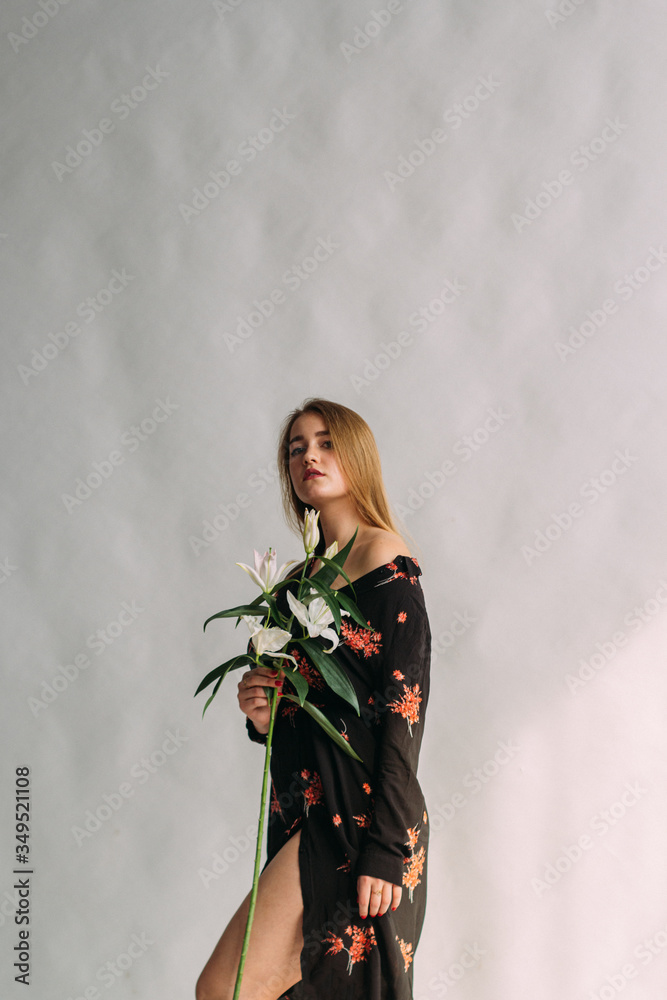 .A young girl with open parts of the body holds a lily flower in her hand. Gentle look. Stock photo with blank space for text.