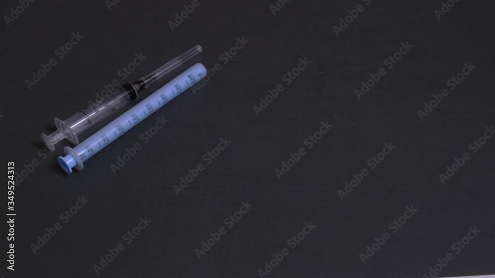 Multi-colored pills fall on a gray background. On a gray background gloomy injection, pills. The concept of medicine and drug addiction. Multi-colored pills fall on a gray background. On a gray background gloomy injection, pills. The concept of medicine and drug addiction.