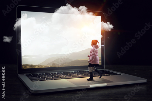 Little girl walks towards huge laptop