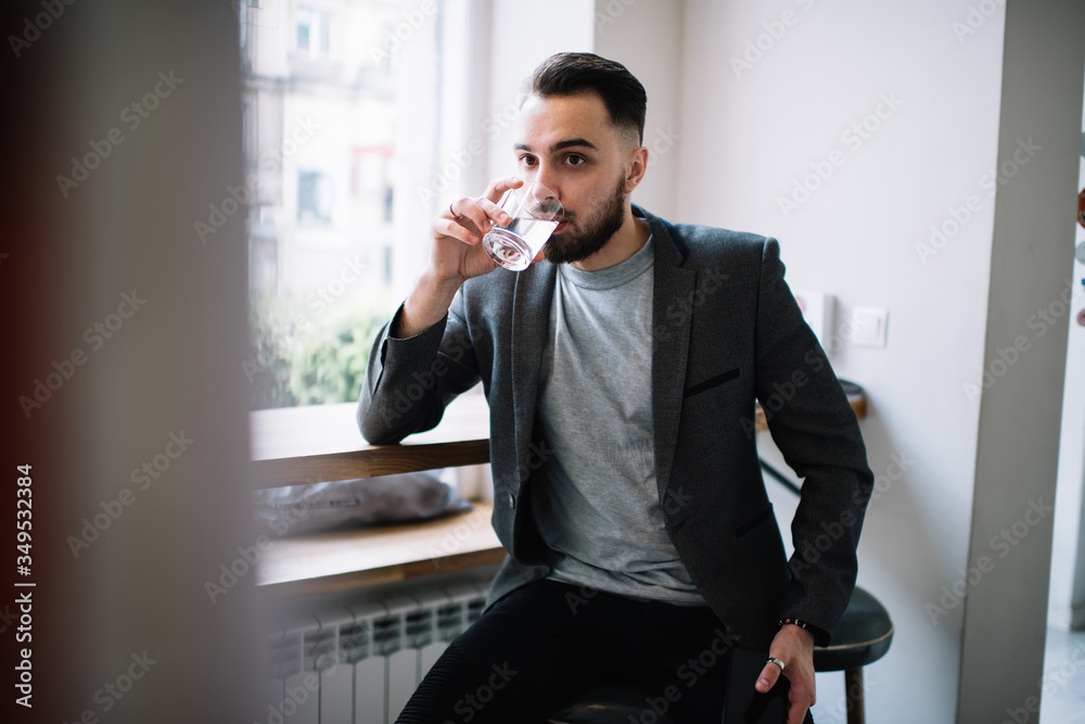 Thoughtful thirsty young man drinking water in cafe Thoughtful thirsty young man drinking water in cafe