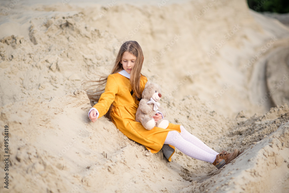 young woman in a yellow dress. little girl playing on the beach. young woman with teddy bear. Girl travels with her favorite toys. young woman in a yellow dress. little girl playing on the beach. young woman with teddy bear. Girl travels with her favorite toys.
