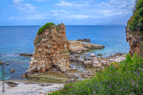 Beautiful landscape - turquoise sea water and cracked, ruined cliff, covered with green grass. Corfu Island, Greece. Kassiopi village. photo