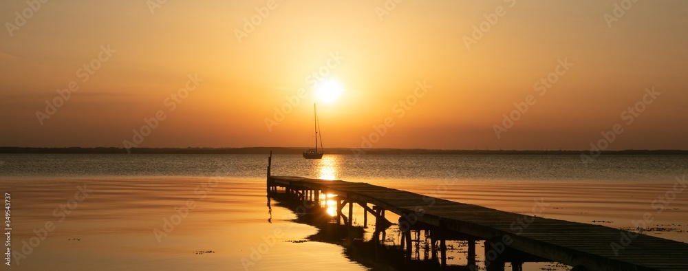 sailboat with jetty at sunset