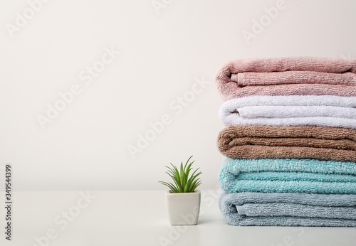 Stack of bath towels and home plant stand on white background