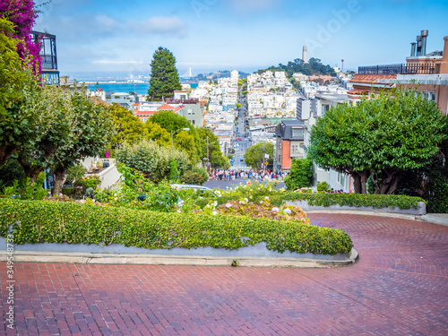Lombard Street, east west street in San Francisco, California famous for a steep, one block section with eight hairpin turns. Victorian houses and bay in the background.