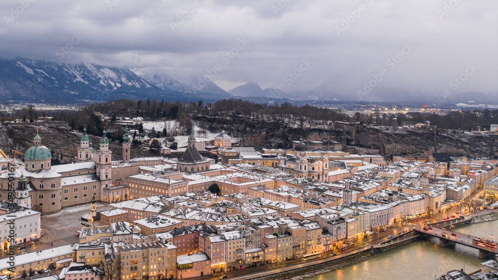 Aerial drone overview of Westside of snowy Salzburg old town and Kollegienkirche Church in Austria in winter