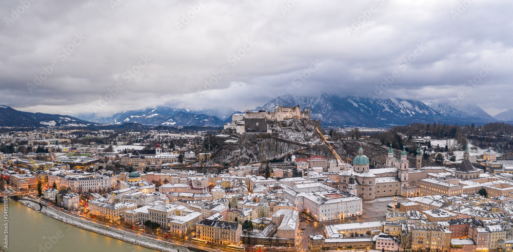 Aerial drone overview of Salzburg old town skyline covered with snow and view of Hohensalzburg in Austria winter