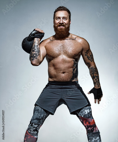 Muscular man training with kettlebell. Photo of man with naked torso on grey background. Strength and motivation © Romario Ien