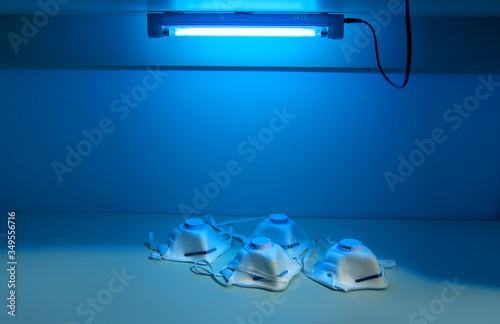 Respirators N95 are sterilized under ultraviolet light. UV sterilization of protective masks in hospital. COVID-19 prevention concept.