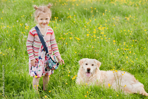 A little blond girl with her pet dog outdooors in park photo