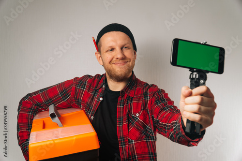 builder is a man of Caucasian portrait as taking selfie on smartphone.
