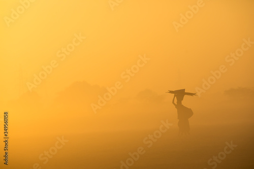 silhouette of a woman in the sunrise carrying load
