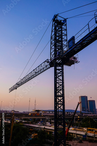 Industrial construction cranes and building silhouettes twilight
